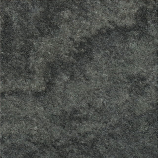 A close-up view of a dark gray to black granular granite surface, featuring an uneven and slightly speckled texture. This image represents the raw material often used as a background for memorial engravings.