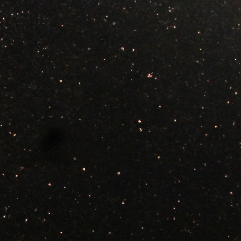 A detailed close-up of a black granite surface, showcasing its inherent sparkling flecks against a deep, dark background. This natural stone texture is often chosen for its elegant and enduring visual appeal on memorials and headstones.