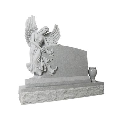 A detailed relief carving on a granite memorial, featuring an angel with outstretched wings gently releasing three doves into flight. The artwork conveys a sense of peace and spiritual ascent, suitable for a gravestone or monument.