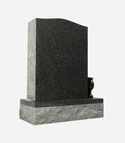 A modern upright headstone crafted from dark gray speckled granite, featuring a gently curved top edge and a polished base. A small, matching granite vase sits on the right side of the base, elegantly contrasting with the rougher texture of the lower foundation.